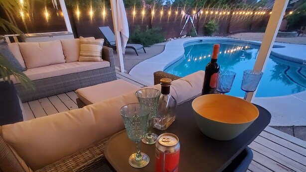 A poolside setting with a table, a bottle, a bowl, and a can.