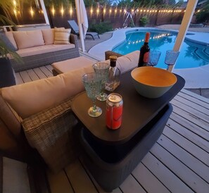 A poolside setting with a table, a bottle, a bowl, and a can.