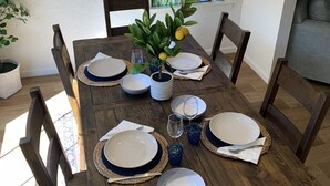 A wooden dining table set with plates, glasses, and a centerpiece.