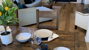 A dining area with a wooden table set for four, a sofa, and a mural of mountains.