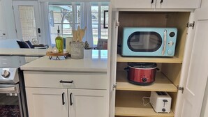 A kitchen with white cabinets, a microwave, a slow cooker, and a toaster. - Remodeled home with firepit! 1 mile to Randolph AFB & 3 parks! (Universal City)