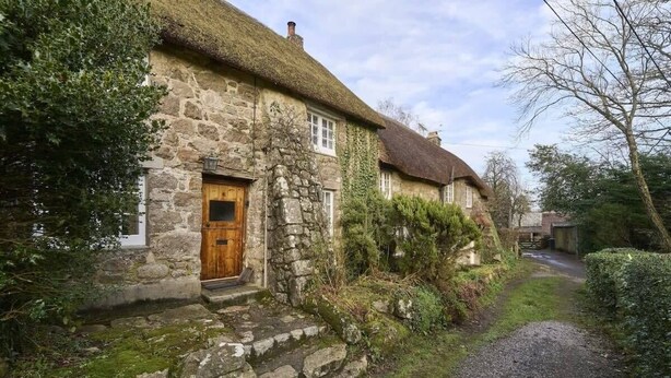 A stone cottage with a thatched roof, a wooden door, and a narrow gravel path leading to it. - Beautiful Thatched Cottage in Heart of Dartmoor (Newton Abbot)