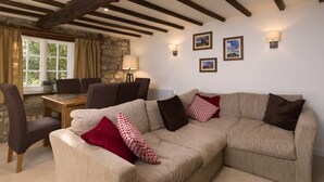 A cozy living room with a sofa, chairs, a table, and a stone wall. - Beautiful Thatched Cottage in Heart of Dartmoor (Newton Abbot)