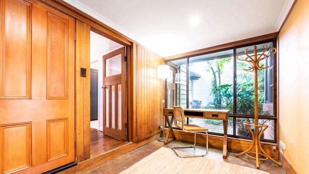 Une porte en bois, un bureau avec une chaise et une fenêtre donnant sur un paysage verdoyant.