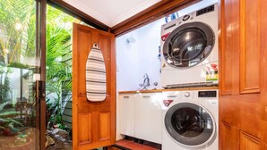 Une buanderie équipée d’un lave-linge et d’un sèche-linge, de meubles en bois et d’une porte sur laquelle est accrochée une serviette à rayures.