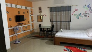Une chambre à coucher avec un lit, un bureau, une chaise, une télévision et un ventilateur.