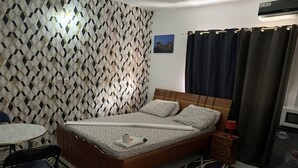 Une chambre à coucher comprenant un lit, une petite table, une chaise, une table de chevet et un four à micro-ondes.