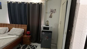Une chambre à coucher comprenant un lit, un petit réfrigérateur, un four à micro-ondes, une table de chevet et un tapis à motifs.