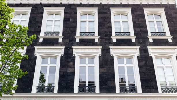 Un bâtiment noir et blanc avec de nombreuses fenêtres et une porte centrale.