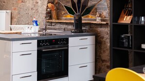 Une cuisine avec un mur en briques au style rustique, un four encastré et des meubles de cuisine modernes blancs.