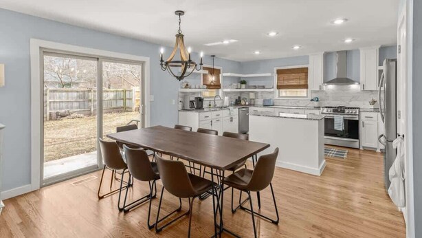 A modern kitchen with a dining area, large windows, and a chandelier. - Spacious Family Haven - Walk to Downtown & JBU (Siloam Springs)