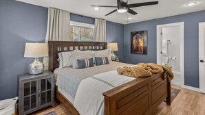 A bedroom with a bed, bedside tables, a ceiling fan, and a window with curtains. - Spacious Family Haven - Walk to Downtown & JBU (Siloam Springs)