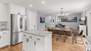 A modern kitchen with white cabinets, stainless steel appliances, and a granite countertop. - Spacious Family Haven - Walk to Downtown & JBU (Siloam Springs)