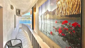 Un couloir orné d’une fresque représentant un paysage côtier, avec une chaise et une rambarde.