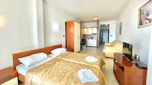 Une chambre d’hôtel avec deux lits, un bureau, une chaise, une kitchenette et une salle de bain.