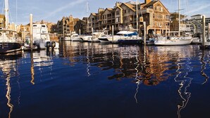 A marina with boats docked, a building with a stone facade, and a clear sky.
