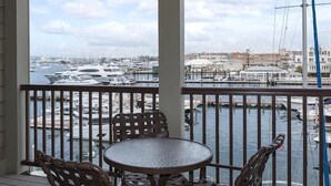 A balcony with a view of a marina, featuring several boats and buildings in the background.