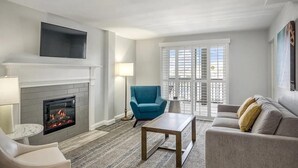 A living room with a fireplace, a blue armchair, a grey sofa, and a coffee table.