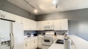 A modern kitchen with white cabinets, a built-in oven, microwave, and a stainless steel sink. - Super close to Disney, 4BR/3BA,Next to the mall(restaurants) (Kissimmee)
