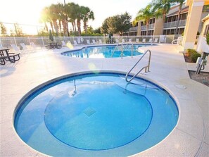 A swimming pool with a metal ladder, surrounded by lounge chairs and a building in the background. - Super close to Disney, 4BR/3BA,Next to the mall(restaurants) (Kissimmee)