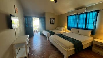 Quarto com duas camas, ventilador de teto, televisão e janela com cortinas.