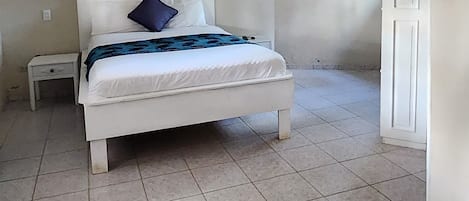 A bedroom with a bed, nightstands, a ceiling light, and an air conditioning unit.