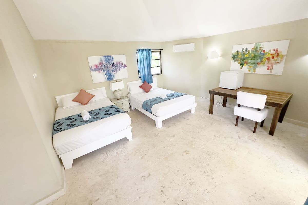 A bedroom with two beds, a desk, and a chair.