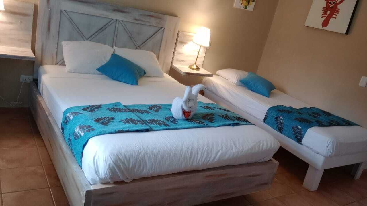 A hotel room with a large bed, a smaller bed, and a nightstand with a lamp.