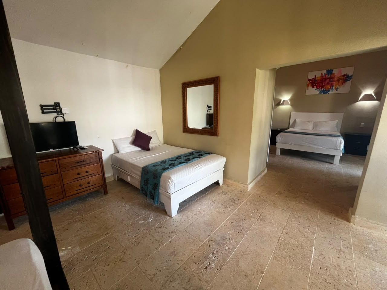 A bedroom with a bed, a dresser, a mirror, and a television.