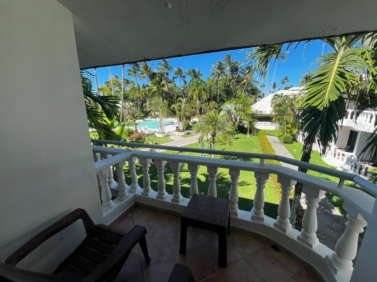 A balcony with a white balustrade, a small table, and a chair.