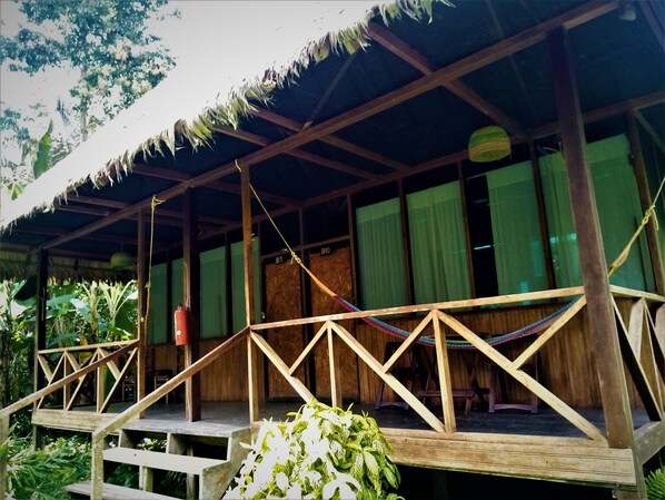A wooden structure with a thatched roof, wooden railings, and a small platform with steps leading up to it.