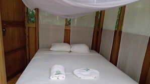 Ein Einzelbett mit weißer Bettwäsche, zwei ordentlich gefaltete Handtücher und einem Baldachin darüber.