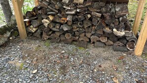 Une structure en bois avec une pile de bois de chauffage en dessous.