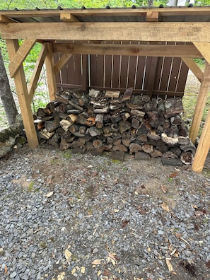 Una estructura de madera con techo que sostiene un montón de leña.