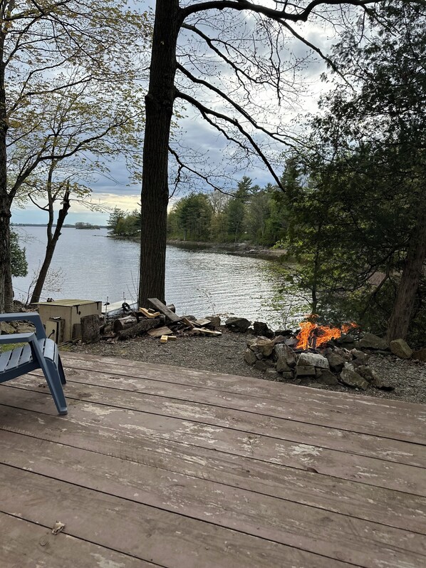 A wooden deck with a fire pit and a bench.