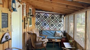 Un intérieur rustique avec des éléments en bois, un tapis vert, des meubles en bois, une tapisserie murale matelassée et un tableau noir sur lequel on a écrit.