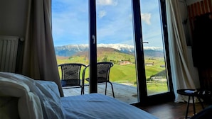 Ein Schlafzimmer mit einer großen Schiebeglasdoor zum Balkon mit Bergblick.