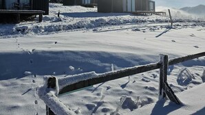 Schneebedecktes Freigelände mit Holzhütten und einem Holzzaun.