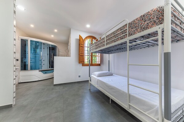 A bunk bed room with a glass door leading to a bathroom, a window with a wooden frame, and a ceiling with recessed lighting. - Large villa with huge garden and swimming pool, perfect for groups and events (Elx)