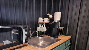 Une cuisine équipée d’un four à micro-ondes, d’un évier et d’une machine à café.