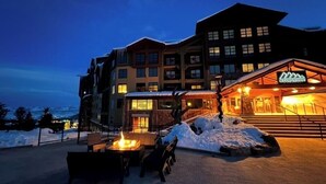 Un hotel con telesilla, asientos exteriores y un paisaje nevado.