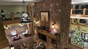 Un hall acogedor con chimenea de piedra, asientos cómodos y un árbol de Navidad.
