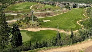 Un campo de golf con club, rodeado de colinas y un cielo despejado.