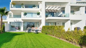 Una casa moderna de dos pisos con césped cuidado y zona de estar al aire libre.