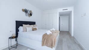 Un dormitorio moderno con una cama grande, una mesita de noche, un adorno en la pared y un armario.