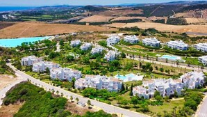 A residential area with white buildings, green spaces, and a swimming pool. - Stylish 2-Bed Apartment | Alcazaba Lagoon (303) (Casares)