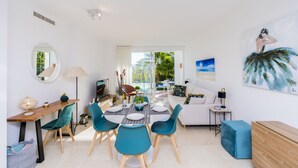 A modern living room with a dining area, featuring a sofa, a coffee table, and a dining table set for four. - Stylish 2-Bed Apartment | Alcazaba Lagoon (303) (Casares)