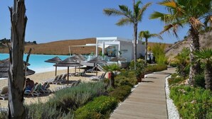 A resort with a pool area, lounge chairs, and a wooden boardwalk. - Stylish 2-Bed Apartment | Alcazaba Lagoon (303) (Casares)