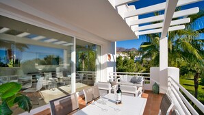 Un patio exterior moderno con una mesa y sillas blancas, y una pérgola.