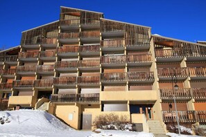 Ein mehrstöckiges Gebäude mit Balkonen, einer Treppe und einem mit Schnee bedeckten Untergrund.